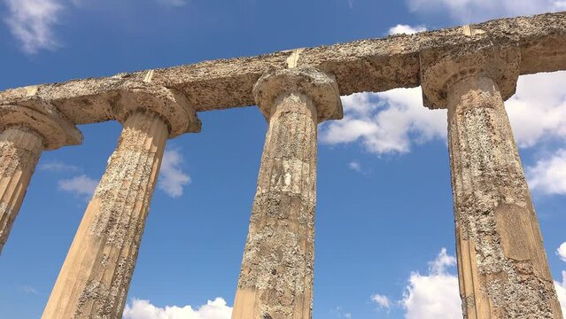 columns of a greek temple with blue sky and white clouds on the background