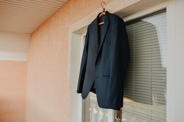 A black jacket hangs against a white window in the room.
