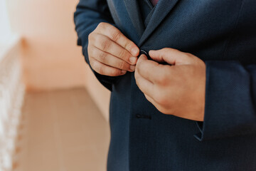 A man in a dark business suit buttoning a button on his jacket.