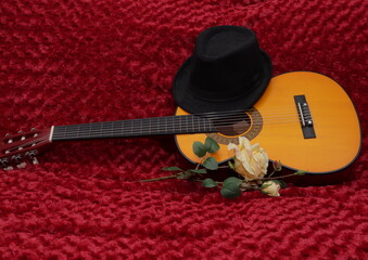 sombrero sobre guitarra rosa amarilla  fondo rojo
