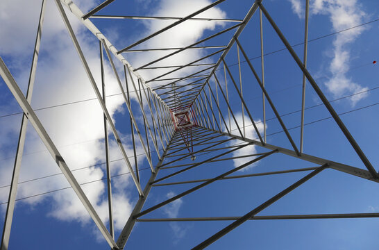 High Voltage Electricity Grid Pylon seen from below with blue sky