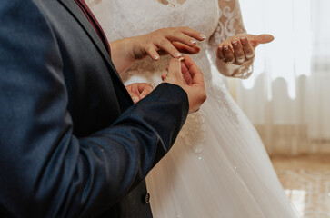 The bride and groom exchange rings. A man puts a wedding ring on a woman's hand.