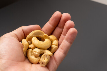Hand holding a handful of cashew nuts.