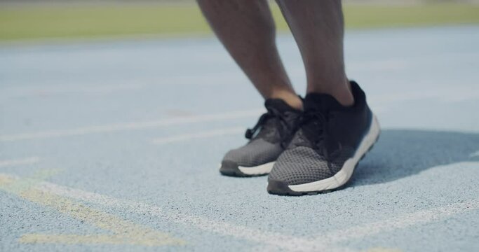 Person, runner and tie shoes for race, sprint or running exercise in outdoor workout on stadium track. Closeup of fitness athlete tying or getting ready for training or competition or challenge