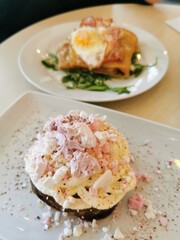 Breakfast and desert crepes. Chocolate pancake covered in white whipped cream and pink crushed meringue. Egg and bacon with arugula pancake