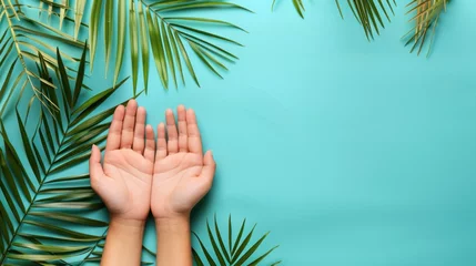 Foto op Canvas hands and green palm leaves on aqua background with copy space © KRIS