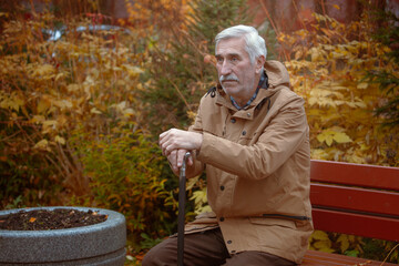 an senior man with a cane sits on a bench in an autumn park,  dementia and alzheimer's disease