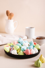 Multi-colored mini meringues on a plate on the table vertical view