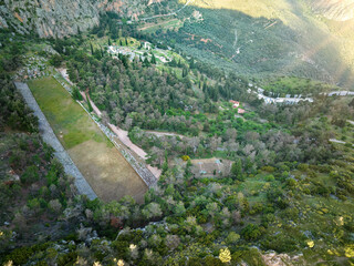 Aerial view of Delphi archaeological site and surrounding hills, UNESCO site, stadium and theatre, evening light, touristic site. Greece.  