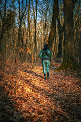 Kobieta ubrana na zielono spacerująca po lesie