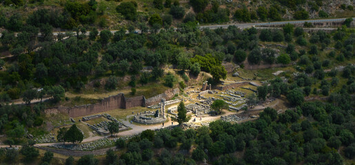 Aerial, panoramic view of illuminated ancient temple complex of Athena Pronaia in Delphi. Archaeological site, UNESCO World Heritage Site.