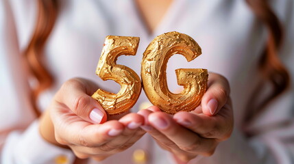 Hands holding a golden 5G symbol, representing the next generation of mobile network technology