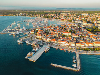 Fototapeta premium Biograd na Moru, aerial view of marina waterfront with ships and yachts at sunset. Waterfront landscape with port and historic architecture of Old Town, Adriatic Sea coast, Dalmatia region in Croatia