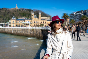 Stylish woman with maroon hat and white coat on Paseo de la Concha