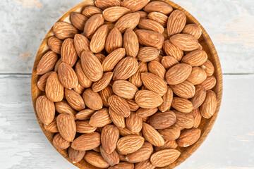 Fresh natural healthy almonds nuts on a wooden plate.