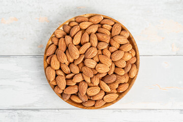 Fresh natural healthy almonds nuts on a wooden plate.