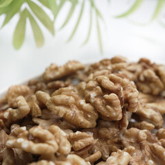 Up-close, the rugged surface of walnut halves is juxtaposed with the soft blur of green foliage in the background, highlighting their natural appeal.