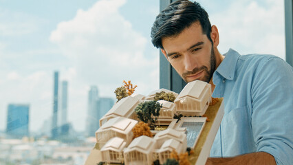 Businessman in casual outfit holding house model while checking house construction. Architect...
