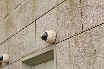 A close up photo of a round security camera attached to the wall 