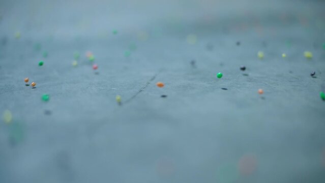 Colorful candy bouncing across a concrete floor in slow-motion.