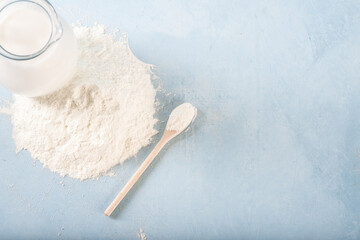Powdered milk on a blue background with a jug of whole milk