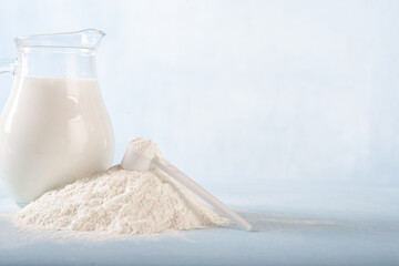 Powdered milk and whole milk in a jug on a light blue background