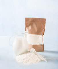 Powdered milk and whole milk in a jug on a light blue background