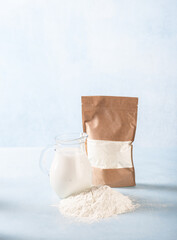 Powdered milk and whole milk in a jug on a light blue background