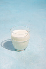 Glass of milk on blue background in sunlight