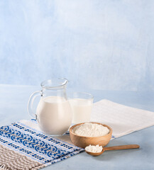 Powdered milk and whole milk in a jug on a light blue background
