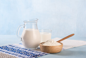 Powdered milk and whole milk in a jug on a light blue background