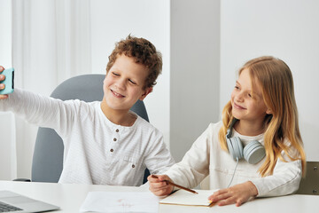 Two Teenage Friends Taking a Selfie on a Smartphone While Sitting and Laughing Together in a Cozy Living Room, Capturing Their Fun and Connection in the Digital Age
