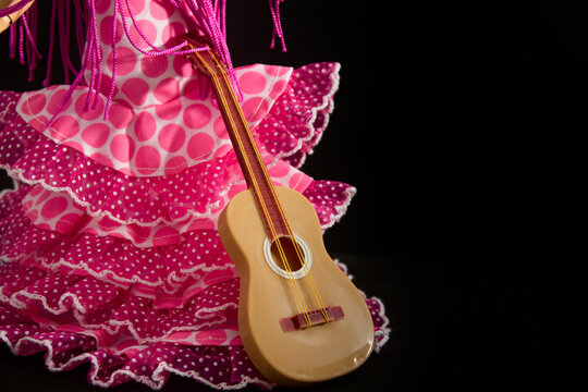 Faralaes costume for a flamenco dancer with a guitar. Black background with copy space