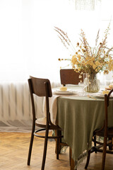 Table with tablecloth and vintage chairs in the room