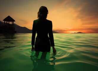 Fototapeta premium Solitary woman wading in mountain lake at dusk with picturesque landscape.