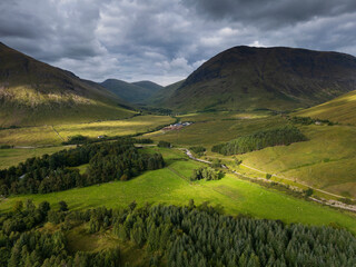 Obraz premium Aerial view of mountains with green grass and forest at Auch, Bridge of Orchy, Scottish Highlands