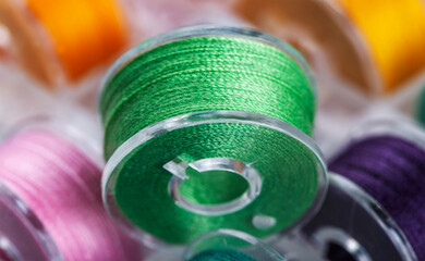 Plastic bobbin with bright green thread close-up