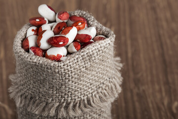white beans with red spots in bags on a wooden table