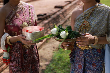 Young beautiful asia woman with Traditonal Thai dress hold lotus flower and Silver Bowl to to temple , Songkran festival concept at Wat Phra Si Sanphet, Ayutthaya