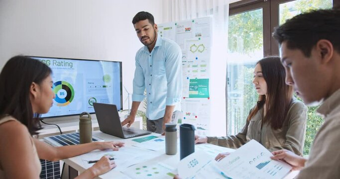 Asian Indian man lead young group of multiethnic businesspeople in team meeting, using laptop computer for ESG topic presentation on monitor. Sustainable business practice, people work at home concept