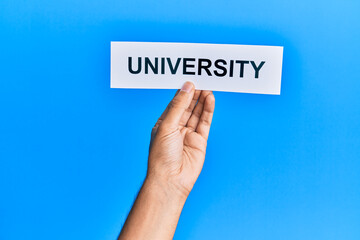 Hand of caucasian man holding paper with university word over isolated blue background