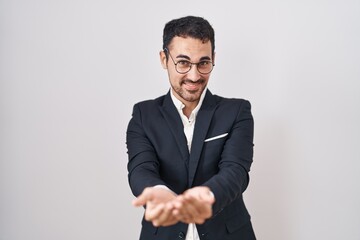Handsome business hispanic man standing over white background smiling with hands palms together receiving or giving gesture. hold and protection