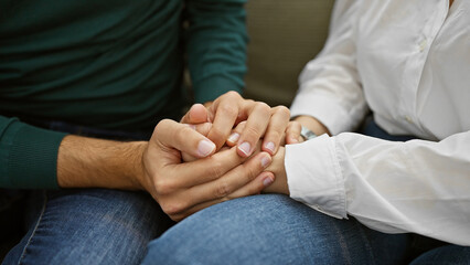 Close-up of a man and woman holding hands, symbolizing love and support indoors.