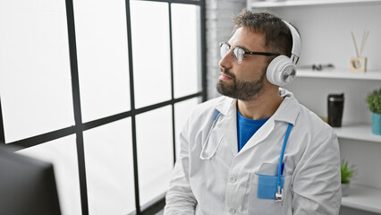 Young hispanic man doctor listening to music at the clinic