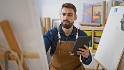 Passionate young hispanic man artist immersed in painting class, effortlessly drawing on laptop...