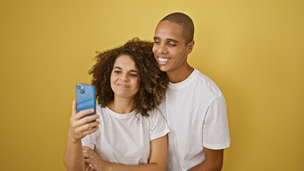 Confident beautiful couple, oozing joy, taking a smiling selfie on their smartphone. standing...
