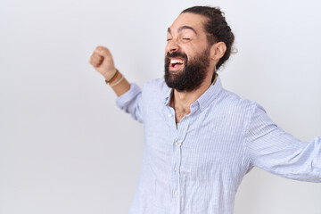 Fototapeta premium Hispanic man with beard wearing casual shirt dancing happy and cheerful, smiling moving casual and confident listening to music