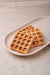 Two Viennese waffles on a beige dish on a table