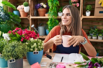 Young beautiful hispanic woman florist smiling confident drinking coffee at flower shop