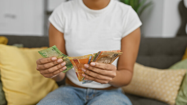 Woman holds south african rands in home interior, showcasing currency, finance, and indoor setting.